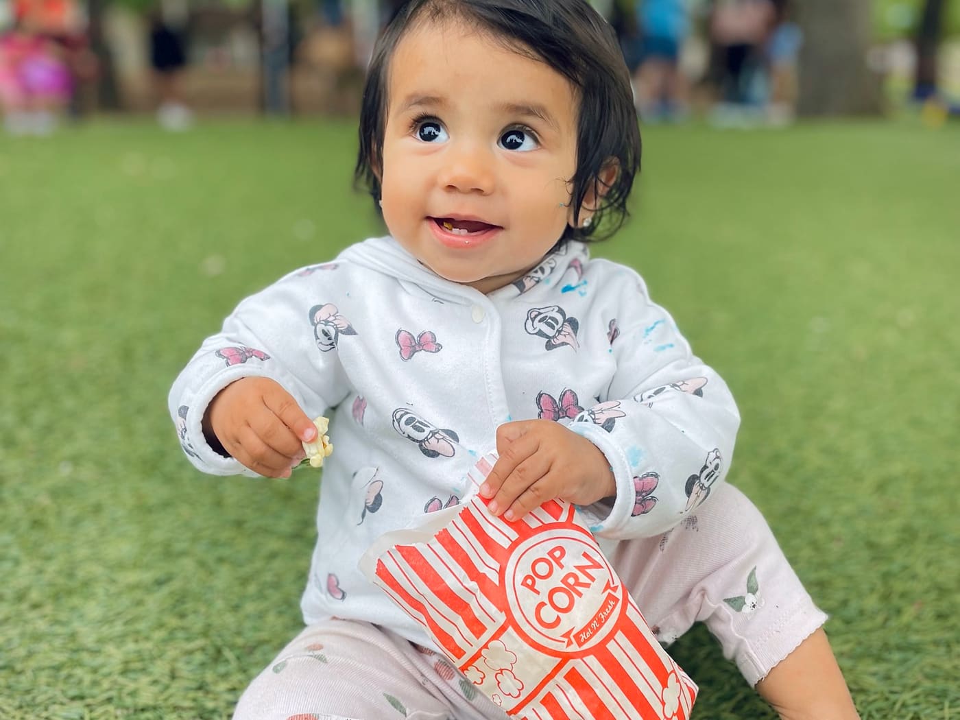 A child at a community festival, popcorn in hand, under the event tents.