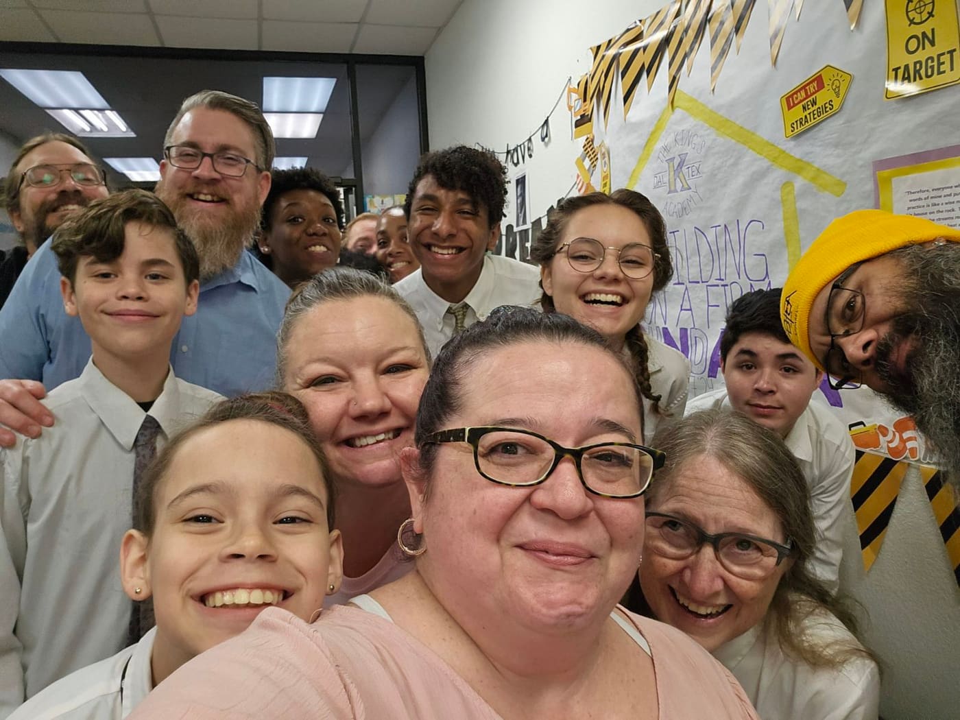 Hosts, volunteers, and students smiling together at a community gathering.